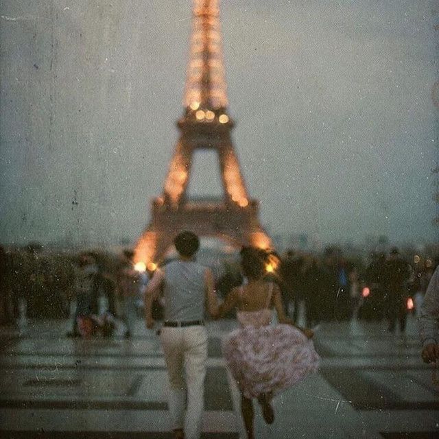 two people walking in front of the eiffel tower