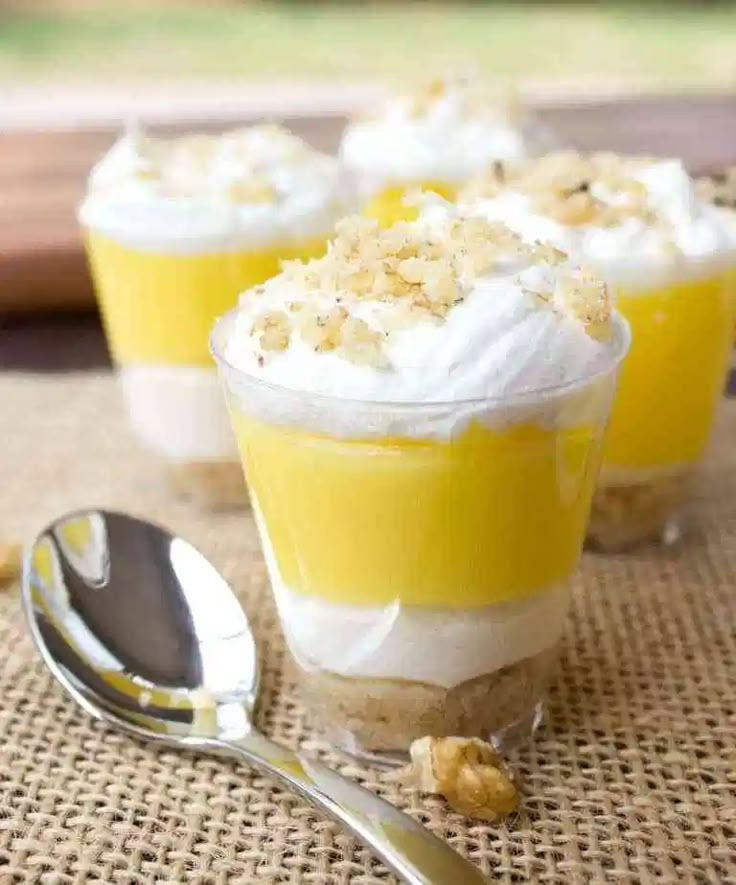 small desserts with meringue and whipped cream are on a table next to a spoon