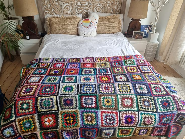 a crocheted blanket on top of a bed in a room with wooden floors