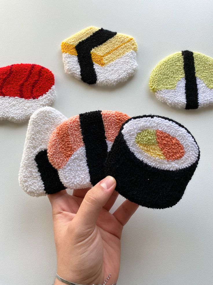 hand holding four sushi coasters in different colors