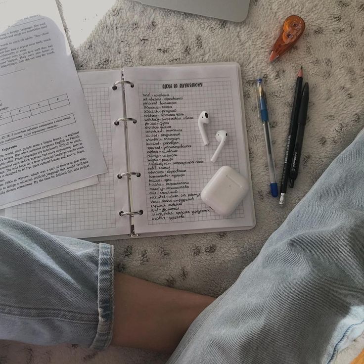 a person's feet on the floor next to an open notebook and headphones