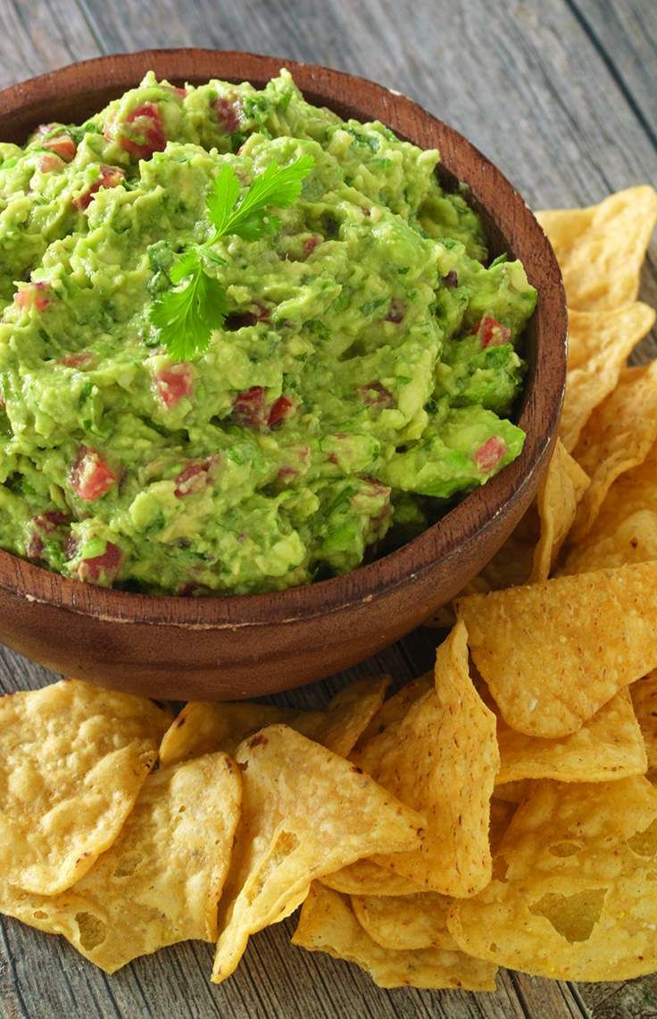 a wooden bowl filled with guacamole and chips