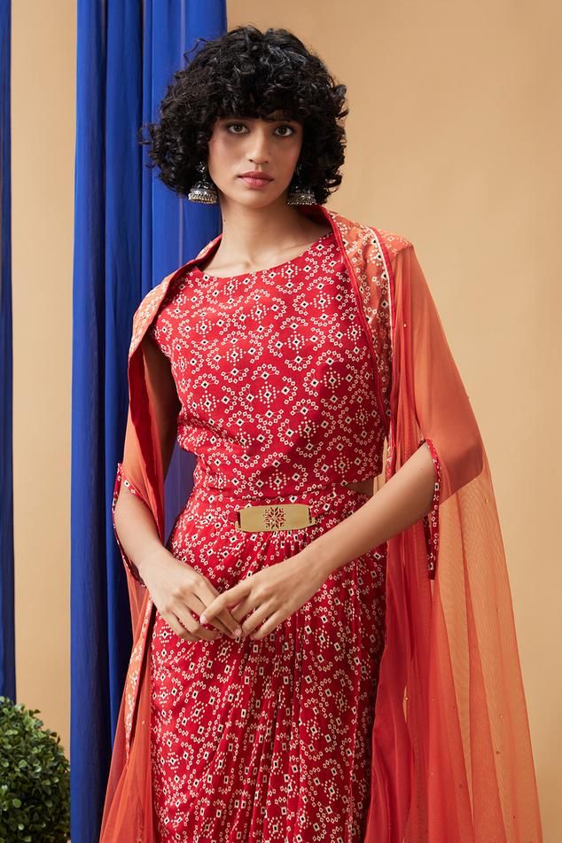 Red crepe dress with bandhej print. Comes with a net cape.
Components: 2
Pattern: Printed
Type Of Work: Bandhej
Neckline: Round
Sleeve Type: Dress: Sleeveless, Cape: Flared Sleeves
Fabric: Dress: Crepe, Cape: Net
Color: Red
Other Details: 
Attached lining
Approx Product Weight: 1 Kg
Closure: Dress - Back zip
Occasion: Party - Aza Fashions Bandhej Dress, Red Crepe Dress, Bandhej Print, Round Dress, Cape For Women, Cape Dress, Crepe Dress, Dress Sleeveless, Flared Sleeves