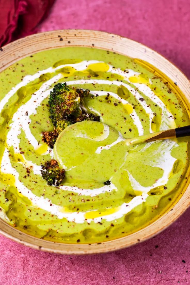 a bowl filled with broccoli and cream on top of a pink table cloth