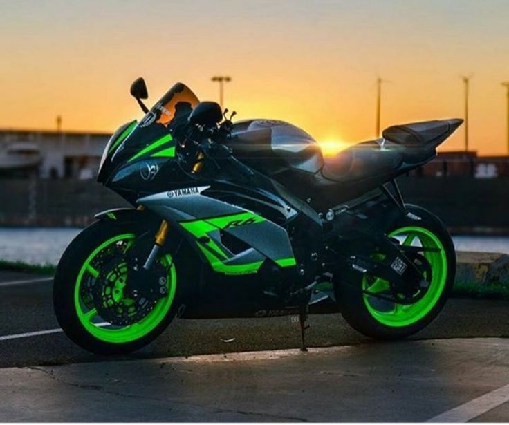 a green and black motorcycle parked on the side of a road at sunset or dawn