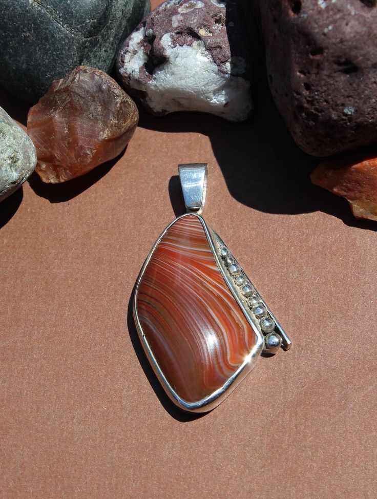 "Lake Superior Agate Pendant set in .950 Sterling Silver with solid silver back. Pretty red and white banding and decorative silver edge. Piece measures about 1.5\" x 1\" chain not included Our reviews will tell you, If you like it here, you'll LOVE it in person! GIVE IT A TRY! If not completely satisfied with your order, contact me right away and return the item within 7 days. FIND WHAT YOU LOVE: Use the \"Sections\" box (or \"Items\" list area) to see the categories. Or use the \"Search Items\" bar to search FUN terms like: eyes, tubes, water level, moon, Easter Island, double, gecko, heart and sale!  Great pictures and information coming to: www.instagram.com/agatejewelrybylarry twitter.com/agatesbylarry" Artisan Agate Jewelry With Polished Finish, Silver Carnelian Cabochon Jewelry, Classic Agate Jewelry With Polished Finish, Red Sterling Silver Jewelry With Polished Finish, Silver Carnelian Jewelry For Anniversary, Formal Agate Pendant Jewelry, Formal Silver Carnelian Jewelry, Classic Red Agate Jewelry, Polished Oval Carnelian Jewelry