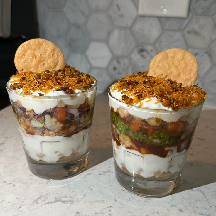 two glasses filled with food sitting on top of a counter next to a cracker