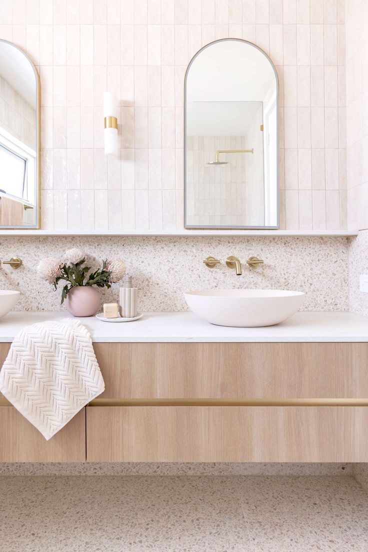 a bathroom with two sinks and mirrors on the wall