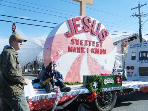 two men are standing on the back of a truck with a large sign behind them