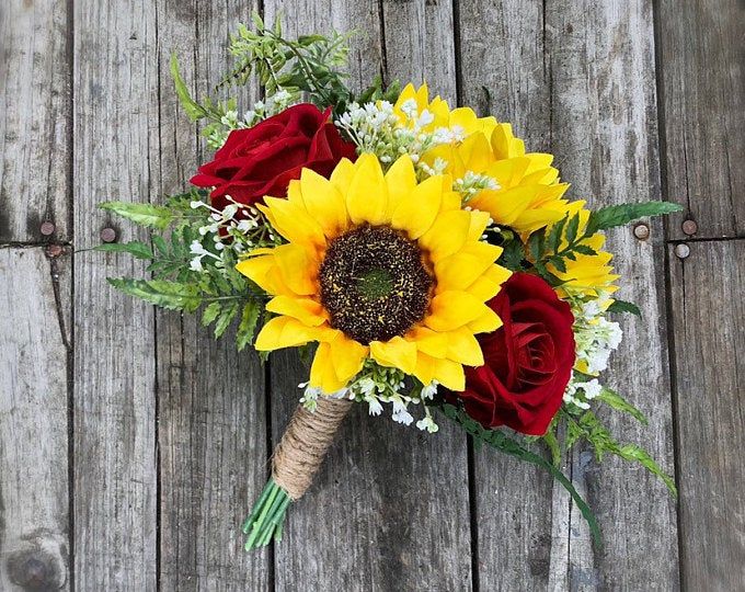 a bouquet of sunflowers, roses and other flowers on a wooden table top