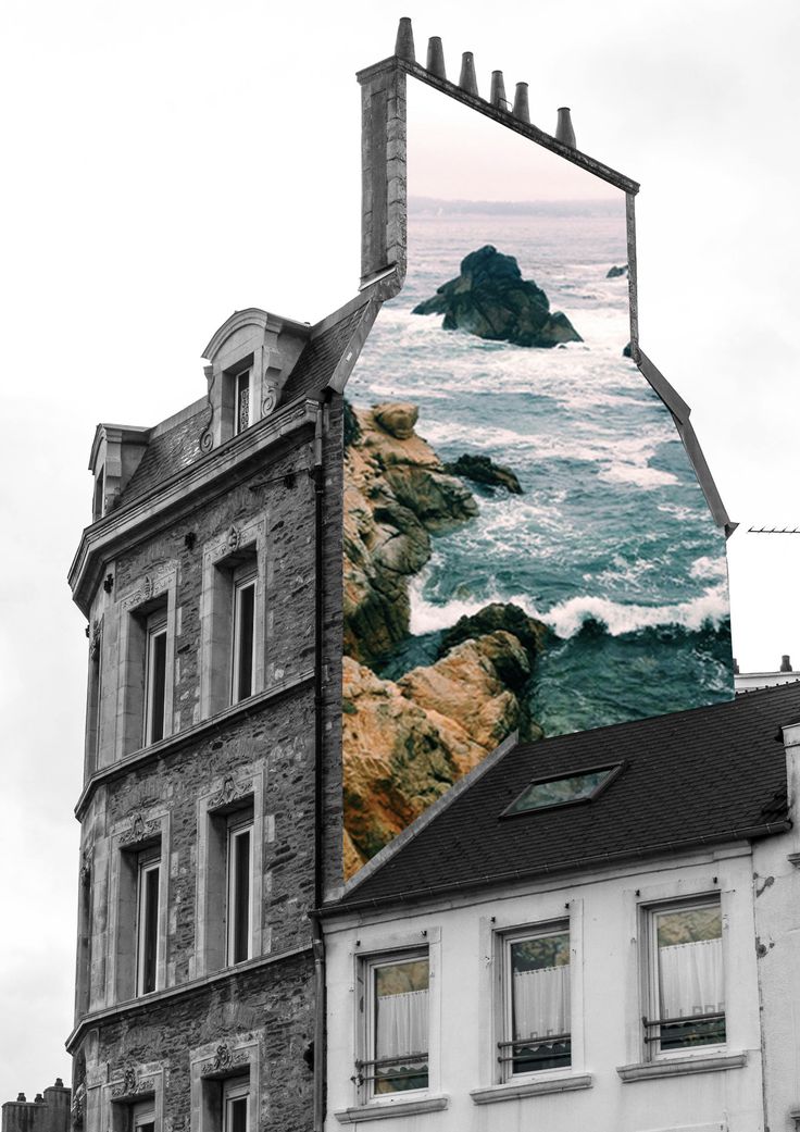 an old building with a large mirror on it's side next to the ocean