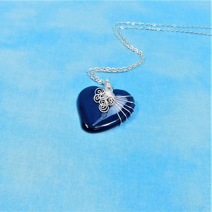 A Blue ceramic heart is artistically hand wire wrapped with non tarnish fine silver over copper wire to create a one of a kind pendant. he heart measures 1 3/4 inches by 1 3/4 inches and comes with a FREE coordinating chain with lobster claw clasp,measured to your preferred length. Your unique pendant necklace is ready to ship via USPS to your US location at no extra cost. (International shipping available. Please be aware of your local laws related to customs and VAT.) Sterling Silver Heart Necklace Wire Wrapped, Blue Pendant Necklace With Copper Wire, Blue Copper Wire Pendant Necklace, Heart-shaped Wire Wrapped Necklace Gift, Heart-shaped Wire Wrapped Necklace For Gift, Unique Heart-shaped Wire Wrapped Necklace, Wire Wrapped Heart Pendant Jewelry Gift, Gift Necklace With Wire-wrapped Design, Handmade Blue Heart Pendant Necklace