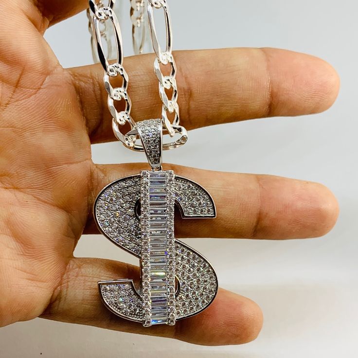 925 Sterling Silver Pendant Money Sign & Figaro Necklace Charm Is 1.5” In Length With White Cubic Zirconia Chain Is 24” & 6.3mm Wide With Diamond Cut On One Side And Plain Opposite Dije Medalla De Plata Dollar Y Cadena Figaro De 24 Pulgadas Frosted Faux Diamond New Jewelry Small Box Included Luxury Custom Silver Necklace, Luxury Custom Silver Necklace With Polished Finish, Silver Iced Out Necklace For Anniversary, Silver Iced Out Pendant Necklace, Iced Out Sterling Silver Necklace For Anniversary, Elegant Iced Out Sterling Silver Jewelry, Luxury Iced Out Sterling Silver Jewelry, Anniversary Iced Out Sterling Silver Necklace, White Diamond Jewelry With Polished Finish