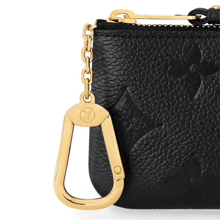 a black and gold purse with a keychain hanging from the front, on a white background