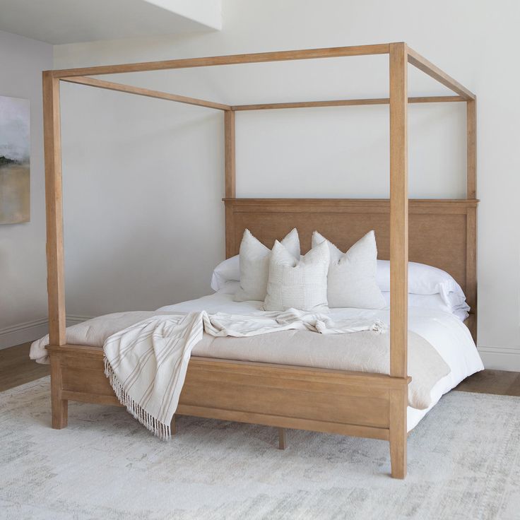 a four poster bed with white pillows and blankets