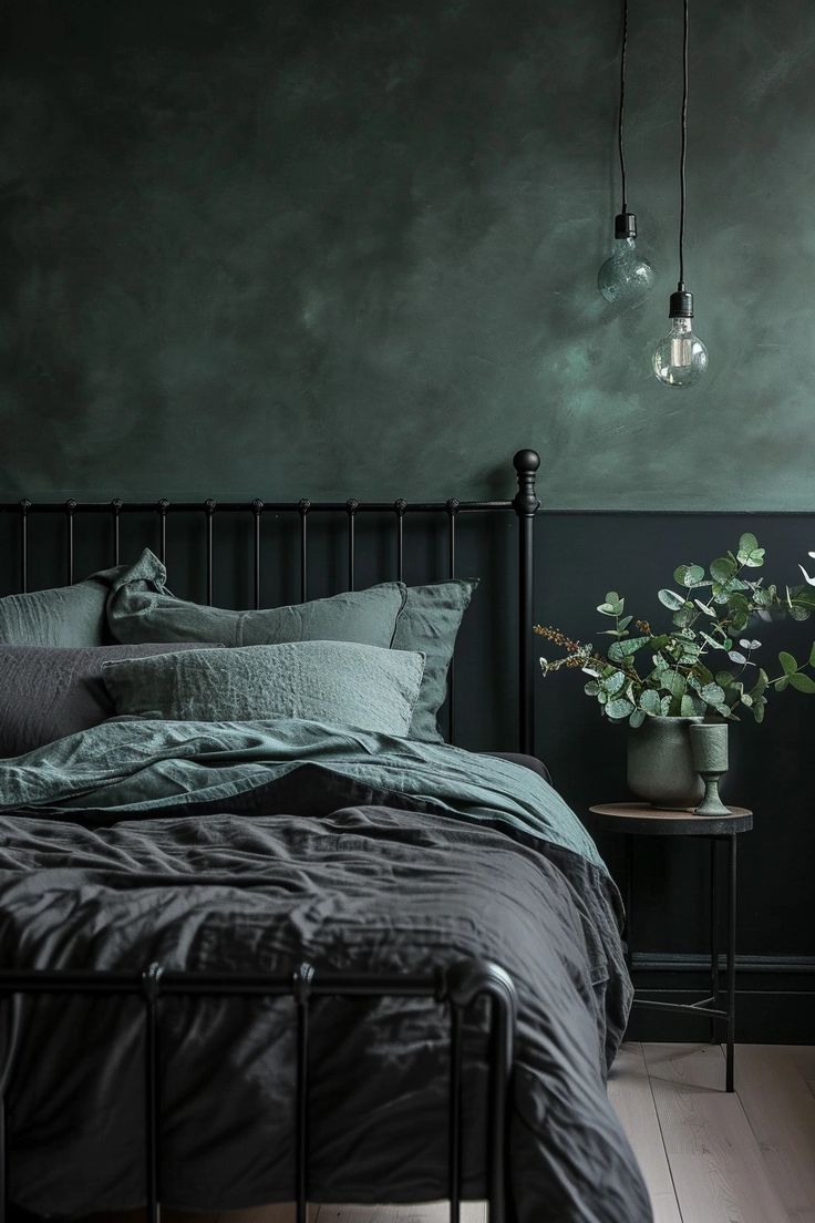 a bedroom with dark green walls and black bedding in the corner, there is a potted plant next to the bed