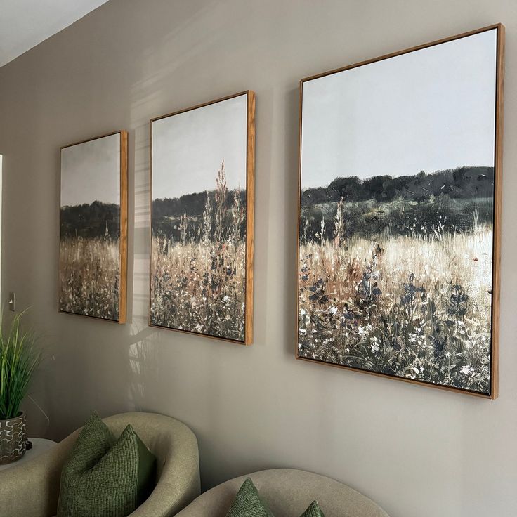 three paintings hang on the wall above a couch