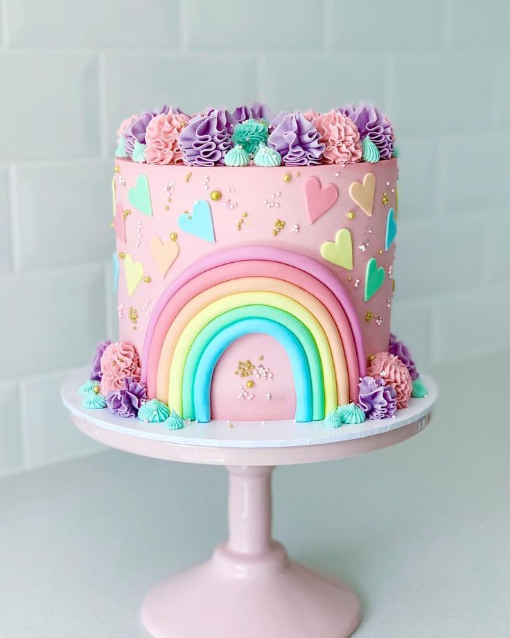 a pink cake decorated with rainbows and hearts