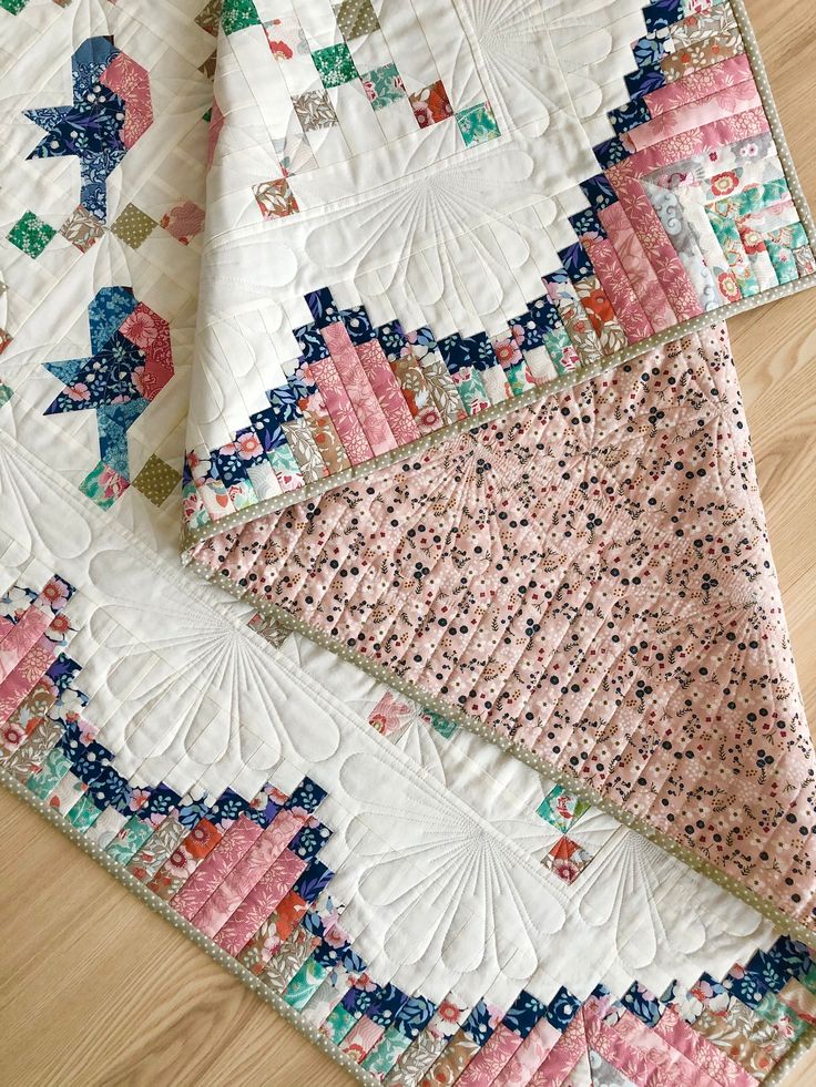 two quilts laying on top of each other in the middle of a wooden floor