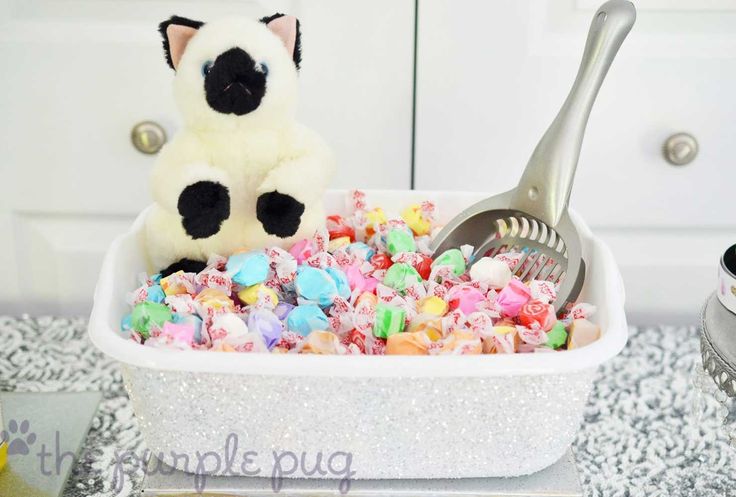 a white bowl filled with lots of colorful candy and a stuffed animal next to it