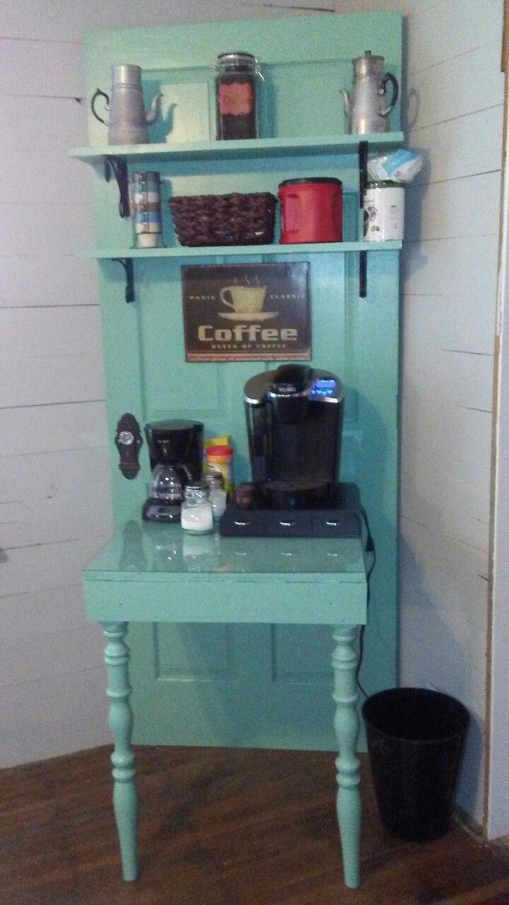 a small blue table with some cups on it and a coffee maker in the corner