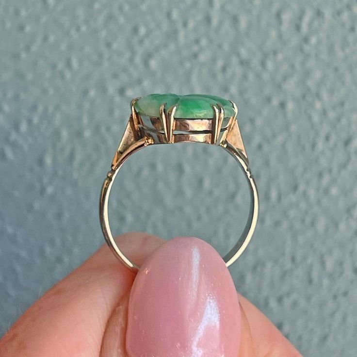 Embodying the spirit of the Art Deco era, this lovely jade ring captures simplicity and beauty in perfect harmony. Crafted in the 1930s, the ring features a graceful split shank mounting in 9 karat white gold, designed to showcase the stunningly carved piece of bright green jade. Its smooth contours and vibrant hue draw the eye, celebrating the natural elegance of the stone.  This beautifully carved, vibrant slice of natural jade measures 18.5 mm north to south and 11 mm across, with a thickness of 2 mm, creating a striking focal point. This ring is a size 6.25 and is marked with '9c' for its 9 karat gold content, weighing a delicate 2.67 grams.  More than just an adornment, this piece invites you to embrace the sophistication of a bygone era, offering a touch of timeless elegance that enh Elegant Jade Ring With Round Band, White Gold Oval Emerald Ring Art Deco Style, Antique White Gold Emerald Ring, Antique Emerald Ring In White Gold, Classic Polished Jade Jewelry, Classic Jade Rings With Polished Finish, Classic Green Opal Ring In 14k Gold, Classic Jade Jewelry, Fine Jewelry Jade Rings With Polished Finish