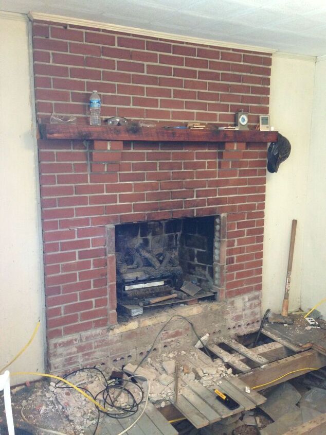 a fire place in the middle of a room being remodeled with bricks and wood flooring