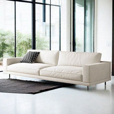 a white couch sitting in front of a window next to a black and white rug