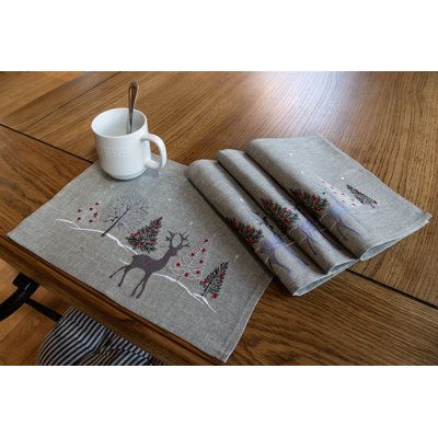 three napkins and a cup on a wooden table with a coffee mug in the middle