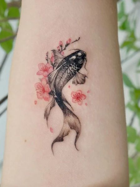 a woman's arm with a fish and flowers tattoo on the left side of her body