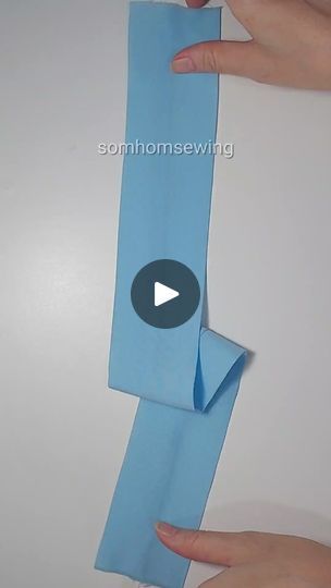 two hands holding an origami piece of blue paper