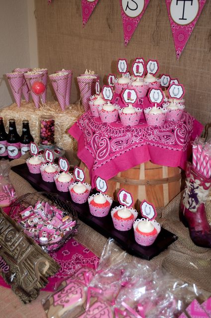 a table filled with lots of cupcakes on top of wooden crates and pink decorations