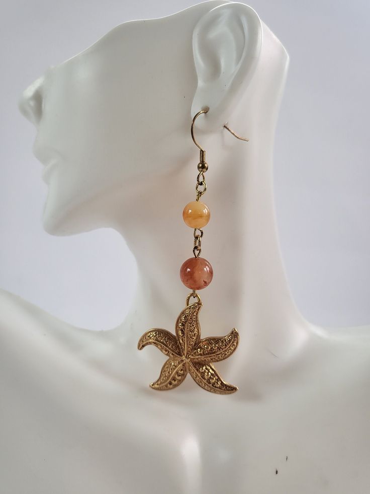 "These were made from two vintage starfish pendants that I lucked out and found on two separate occasions. I used a combo of golden and burnt orange Carnelian beads because when I envision a starfish, the variation with this color.... Asterias Rubens, which is the most common, is the first that pops in my mind.  Feel free to reach out with any questions. Thanks for looking and have a blessed day! Did you know that a starfish can regenerate its limbs at any given time? Or that they can digest prey outside of their bodies, so they are able eat prey much larger than their mouths? Let these little starfish or \"sea stars\" be a reminder to you that after defeat comes growth and even if you bit off more than you can chew, you can still make a feast out of it!" Bohemian Gold Starfish Jewelry, Vintage Handmade Star-shaped Jewelry, Vintage Handmade Star Jewelry, Bohemian Starfish Charm Jewelry For Crafting, Bohemian Starfish Charm Jewelry For Jewelry Making, Bohemian Jewelry With Starfish Charm For Jewelry Making, Bohemian Gold Starfish Charm Jewelry, Handmade Bohemian Starfish Jewelry, Bohemian Gold Jewelry With Starfish Charm