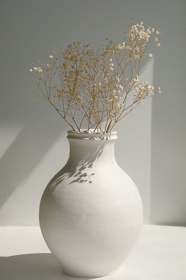 a white vase with some flowers in it