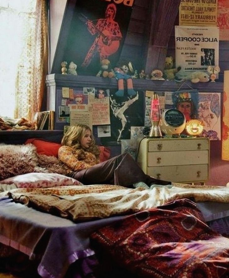 a woman sitting on top of a bed in a room with lots of clutter