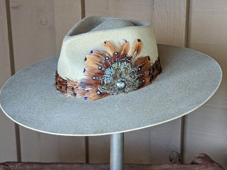 Expertly handcrafted, this wool felt hat is the definition of Nashville fashion. It has a stunning feather hat band and custom made feather fan, that is adorned with a Concho. Perfect for country music and western enthusiasts, this hat is both stylish and unique. The hat is made from 100% wool felt and has a stiff brim that 4" is diameter. The pinch front crown is 4.5" tall. The putty color is a neutral color that will go with just about everything in your wardrobe. Custom Cowgirl Hats, Embellished Cowboy Hat, Feather Hat Band, Art Hats, Nashville Fashion, Cowboy Hat Styles, Hat Burning, Custom Cowboy Hats, Tea Hats