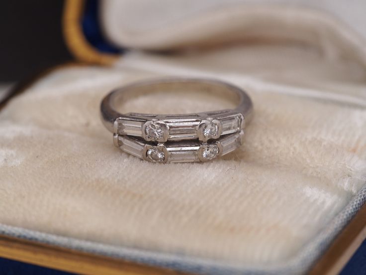 an engagement ring with three baguettes sitting on top of a cloth covered box