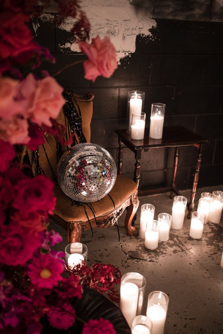 many lit candles are on the floor next to a chair with a mirror ball in it