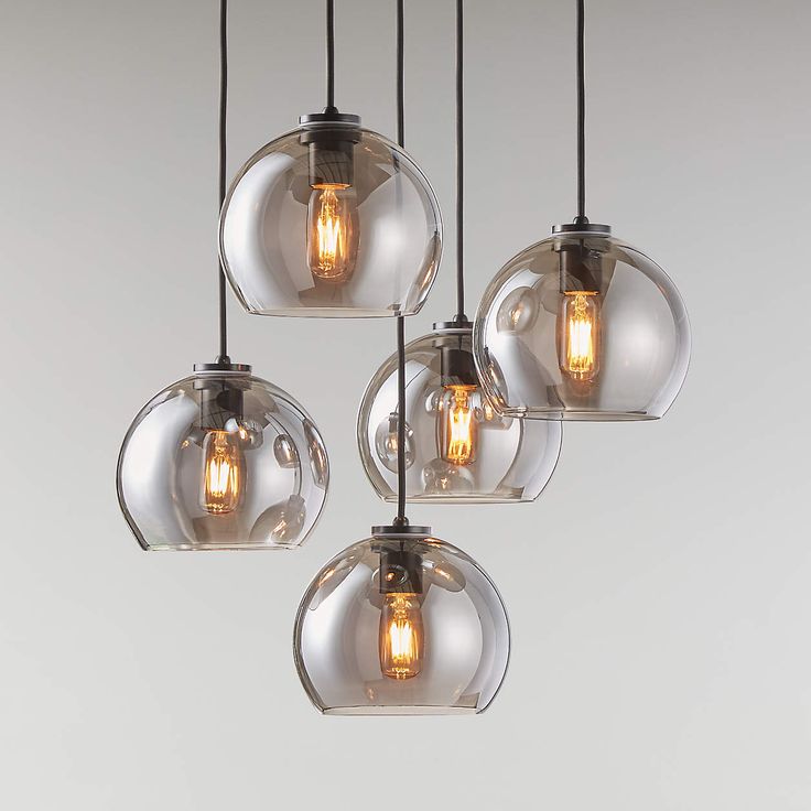 five clear glass globe pendant lights hanging from a ceiling