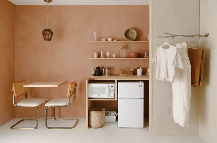 a small kitchen with an open shelf next to a table and two chairs in front of it