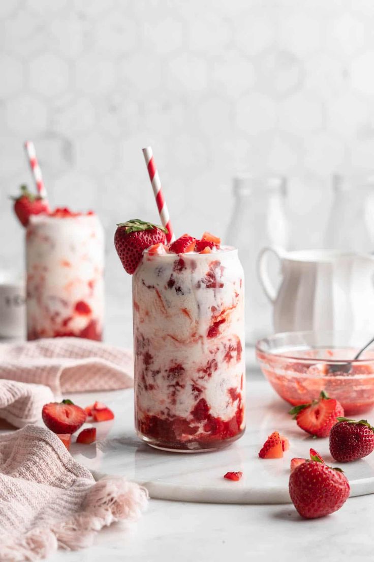 two glasses filled with strawberries and ice cream on top of a white countertop