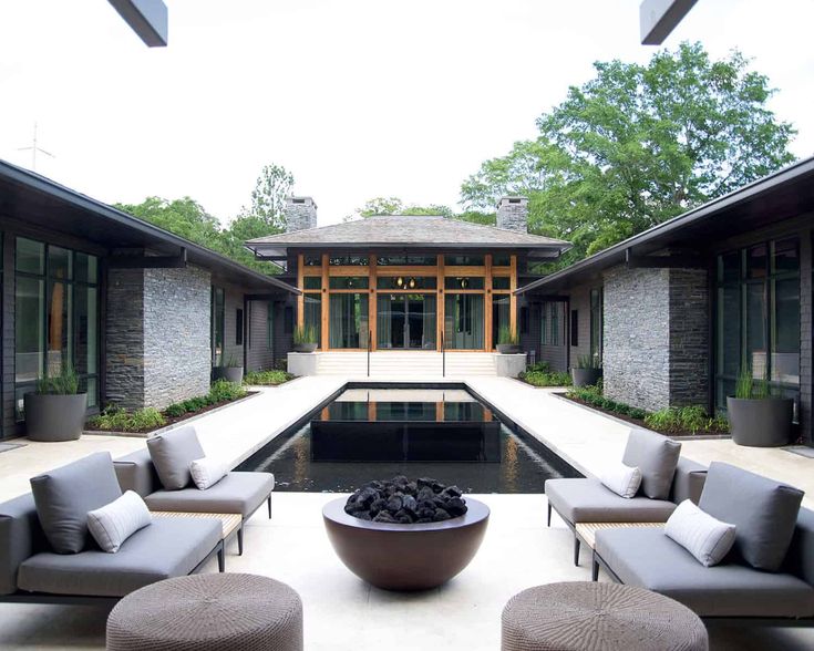 an outdoor living area with couches, chairs and a fire pit in the center