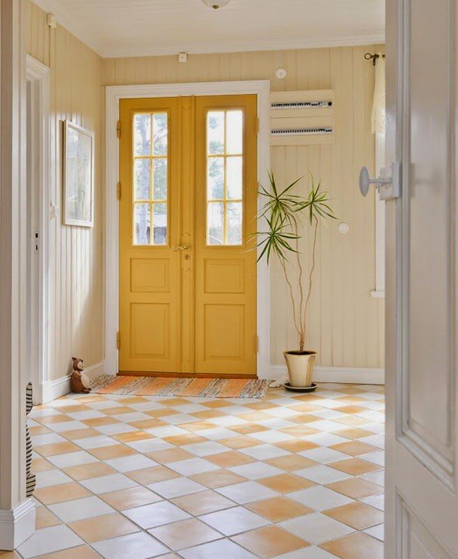 a yellow door is in the middle of a room with white walls and tile flooring