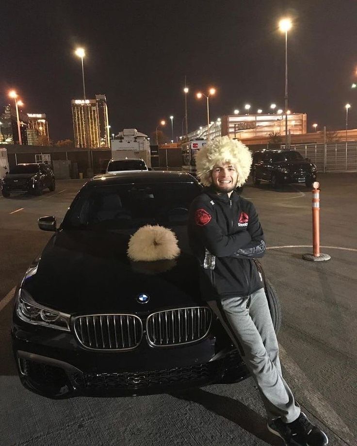 a woman with blonde hair standing next to a black car