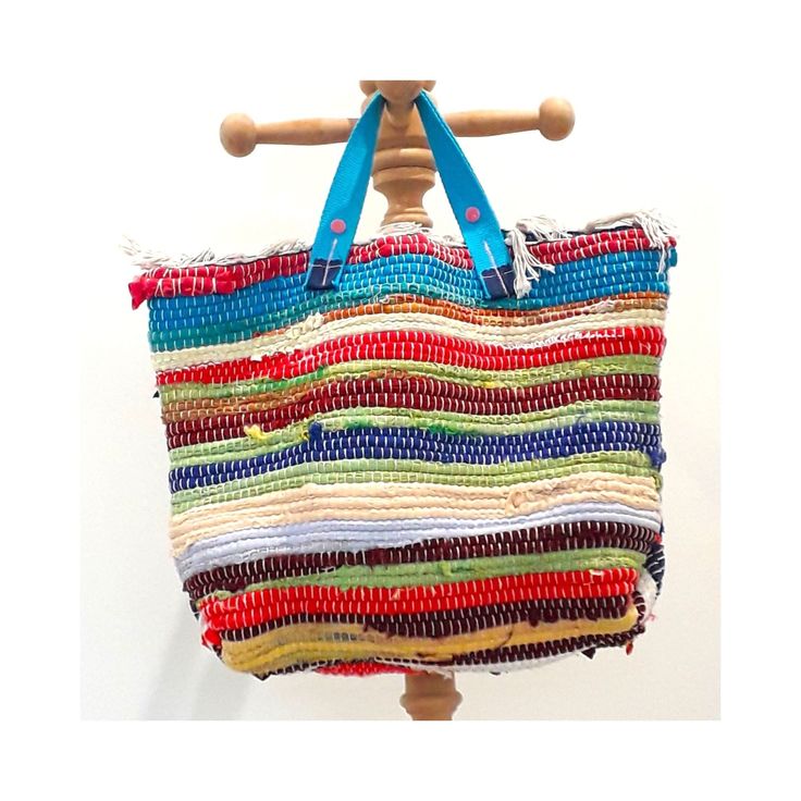 a multicolored bag is hanging on a wooden hanger with blue handles and straps