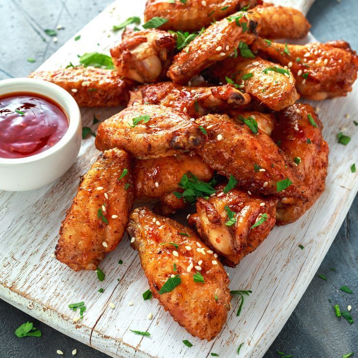 chicken wings with ketchup and sauce on a cutting board, ready to be eaten