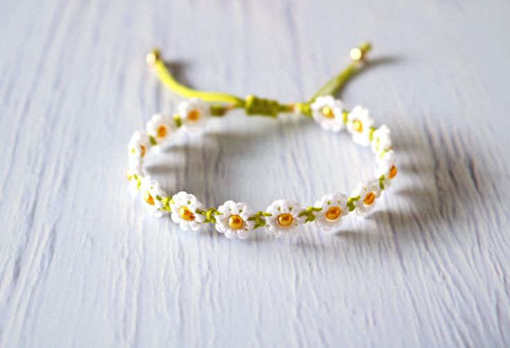 a close up of a bracelet with flowers on it and a yellow ribbon around the wrist