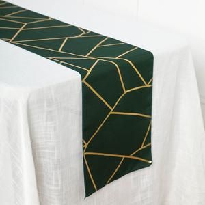 a green and gold table runner on top of a white table cloth with an abstract design