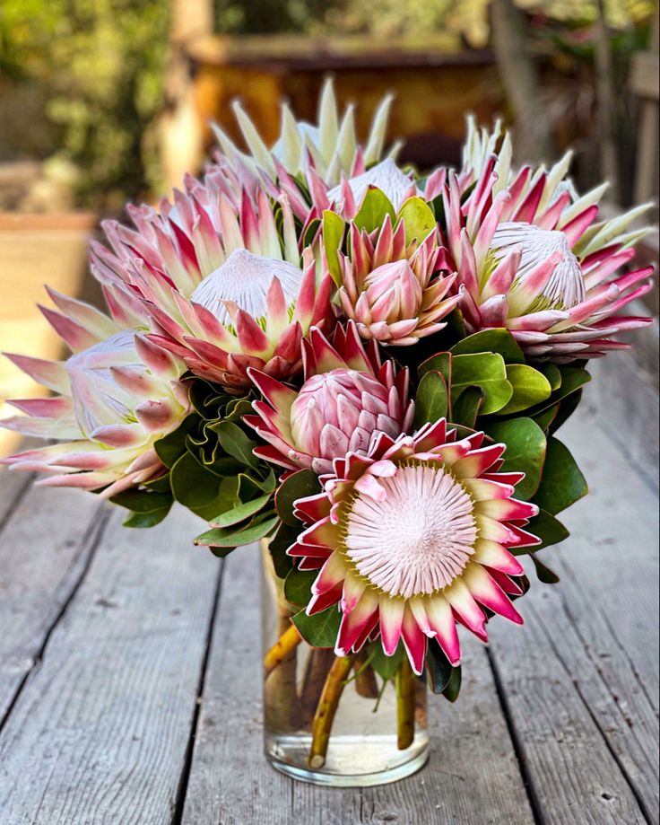 a vase filled with pink flowers on top of a wooden table