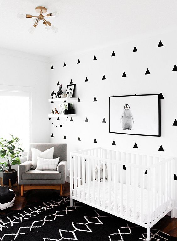 a baby's room decorated in black and white with triangle wall decals on the walls